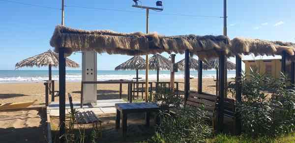 Gazebo con tetto di paglia, tavoli e panche in riva al mare